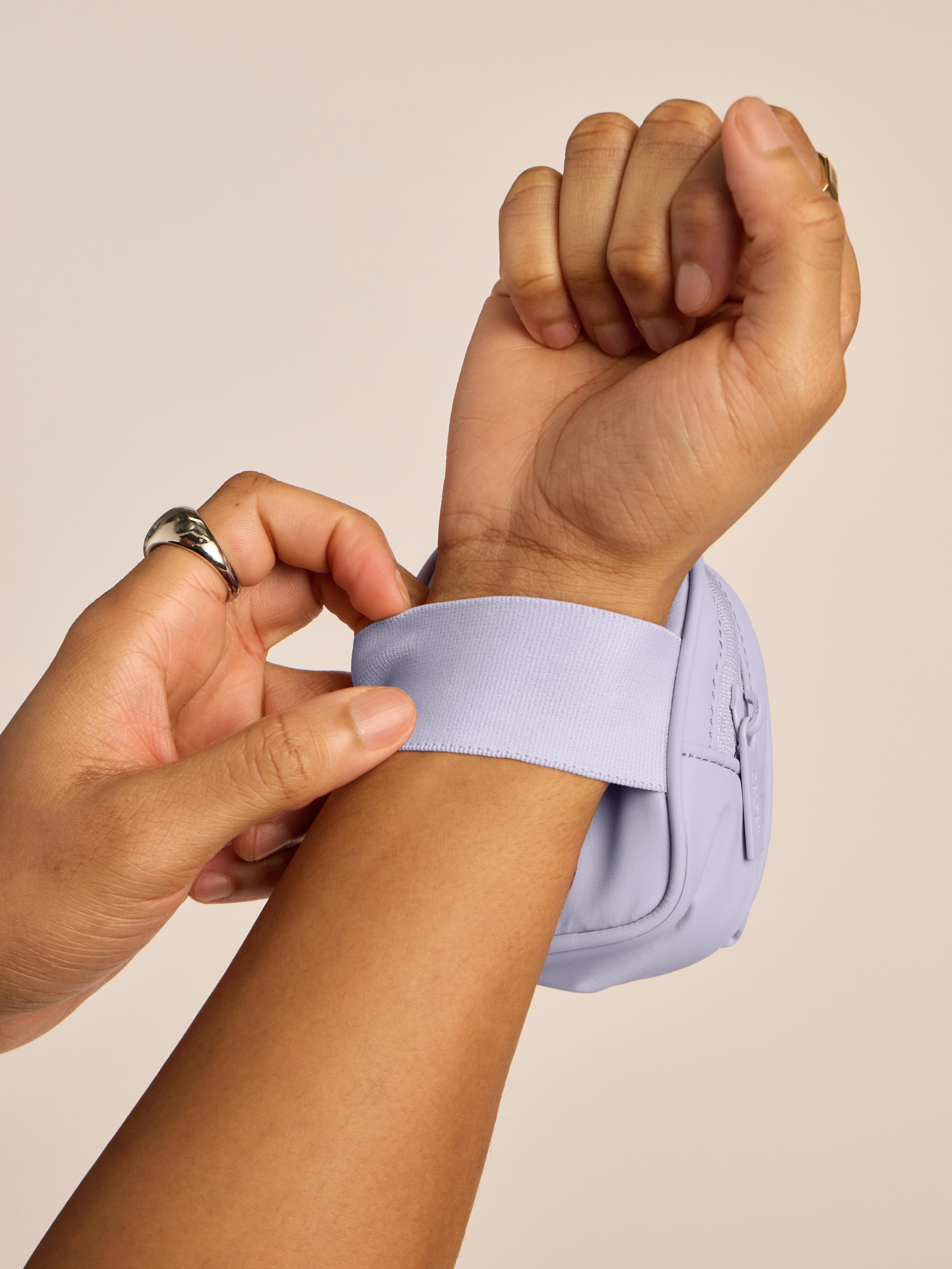 Model putting on CALPAK Luka Keypouch on wrist with strap in lavender purple Orchid; AMB2201-ORCHID