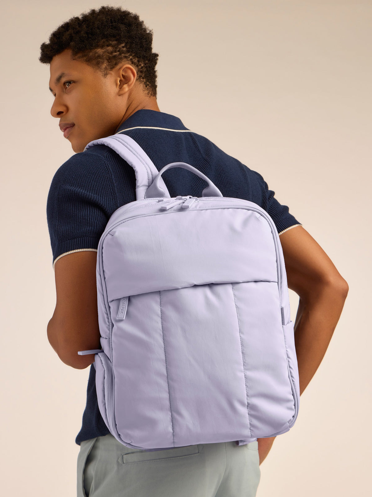 Model wearing CALPAK Luka 15 inch Laptop Backpack in lavender purple in Orchid; BPL2001-ORCHID