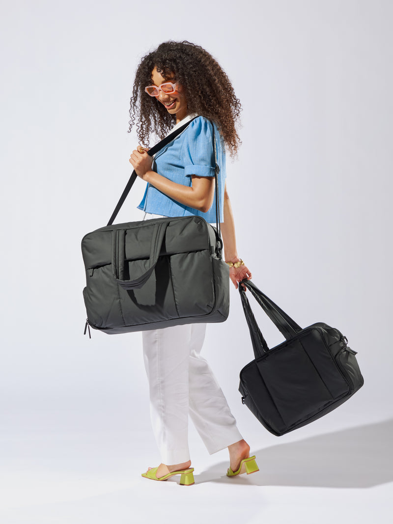 Model wearing the Luka Large Duffel in black and holding the Luka Duffel in black in her other hand