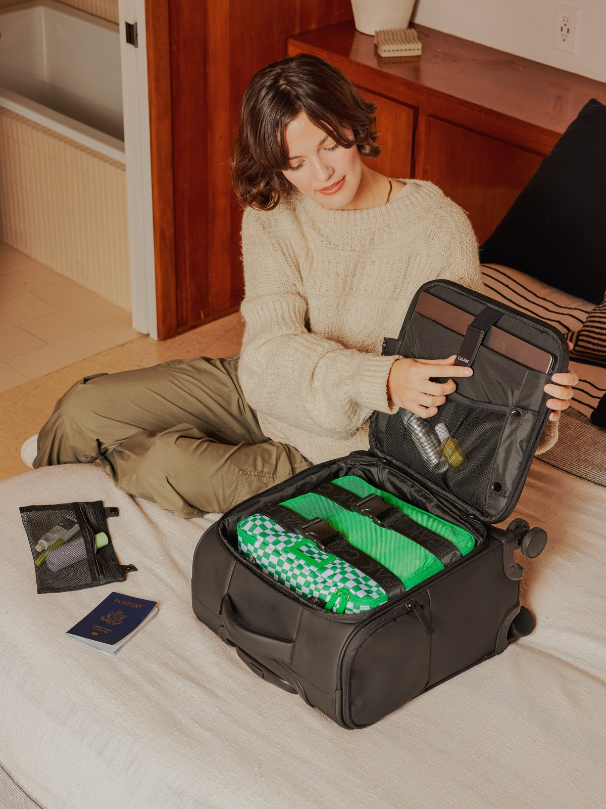 Model packing CALPAK carry-on Luka mini soft luggage with laptop compartment in black; LSM1014-MATTE-BLACK