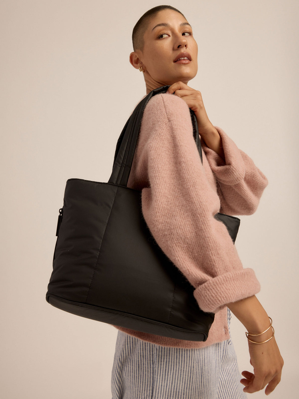 Model wearing black CALPAK Mini Tote durable padded shoulder strap over shoulder; ALM2401-MATTE-BLACK