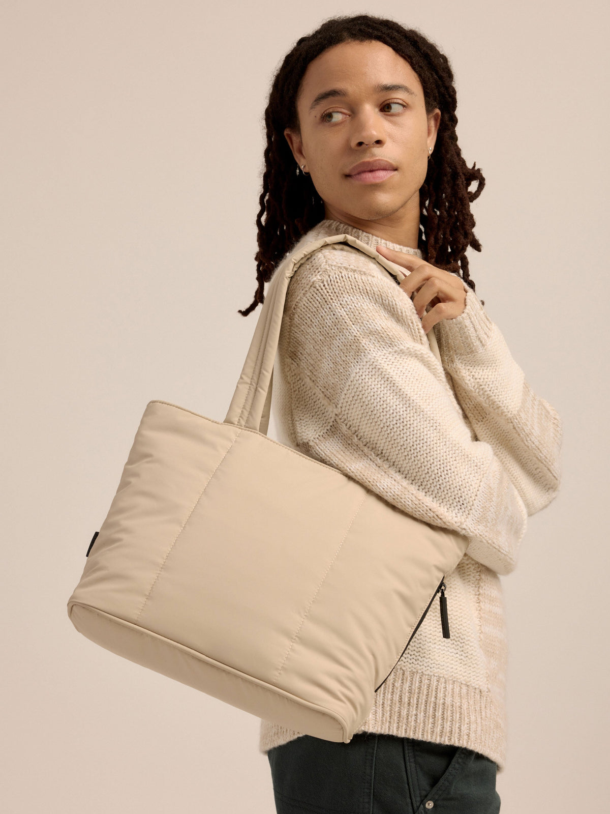 Model wearing soft, puffy CALPAK Luka Mini Tote over shoulder in beige oatmeal; ALM2401-OATMEAL