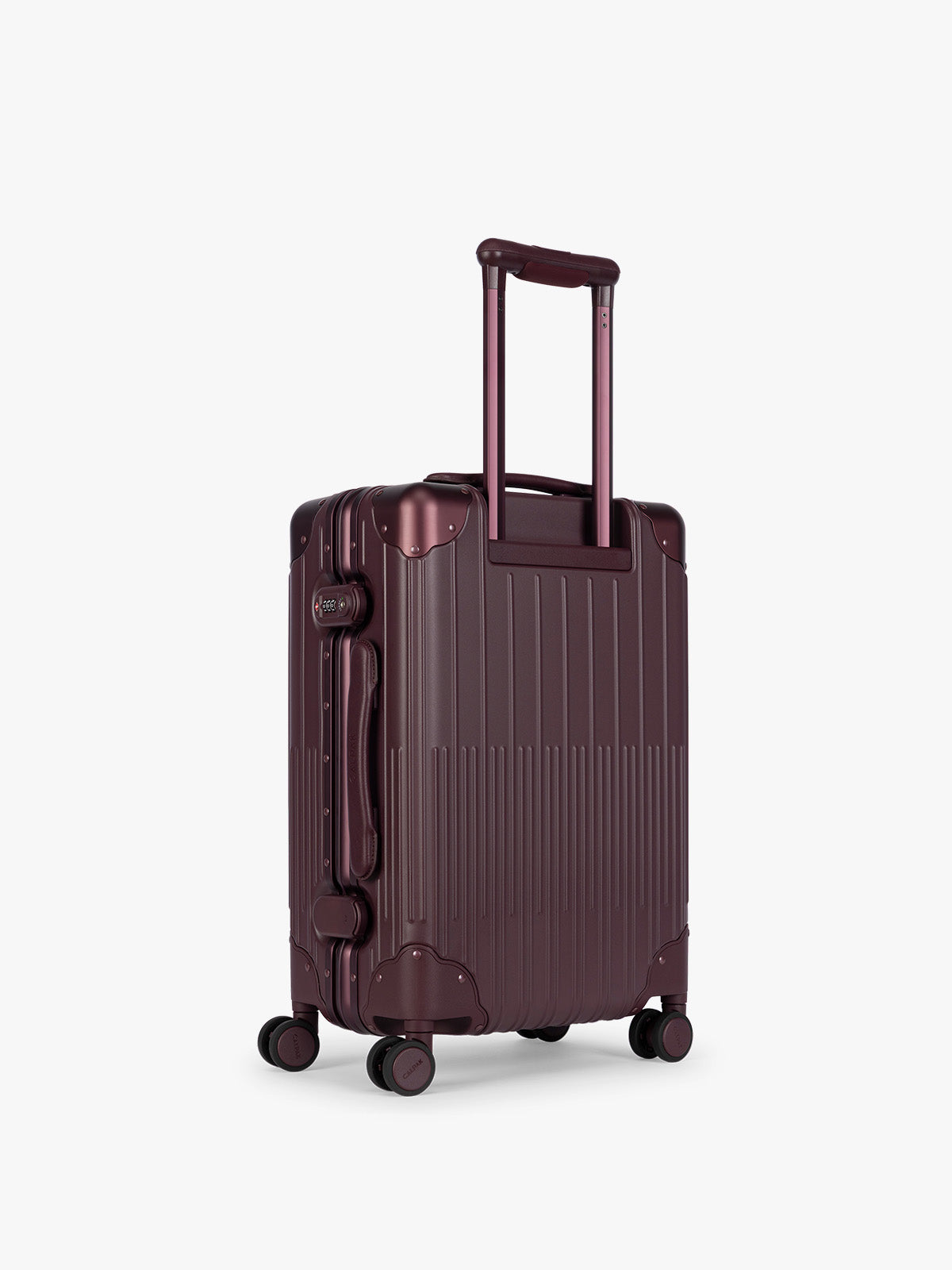 Backside of CALPAK Vault deep red Dark Cherry hard-shell spinner Carry On Luggage with a telescoping handle extended, featuring a deep red leatherette side handle and trim, set against a plain light gray background; LVT1020-DARK-CHERRY