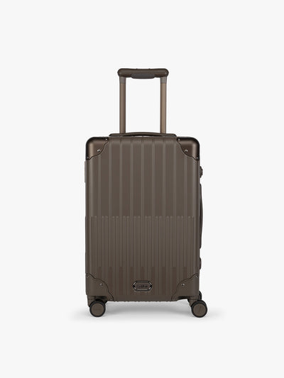 CALPAK Vault brown Mushroom hard-shell spinner Carry On Luggage with a telescoping handle extended, featuring a black leatherette side handle and trim, set against a plain light gray background; LVT1020-MUSHROOM