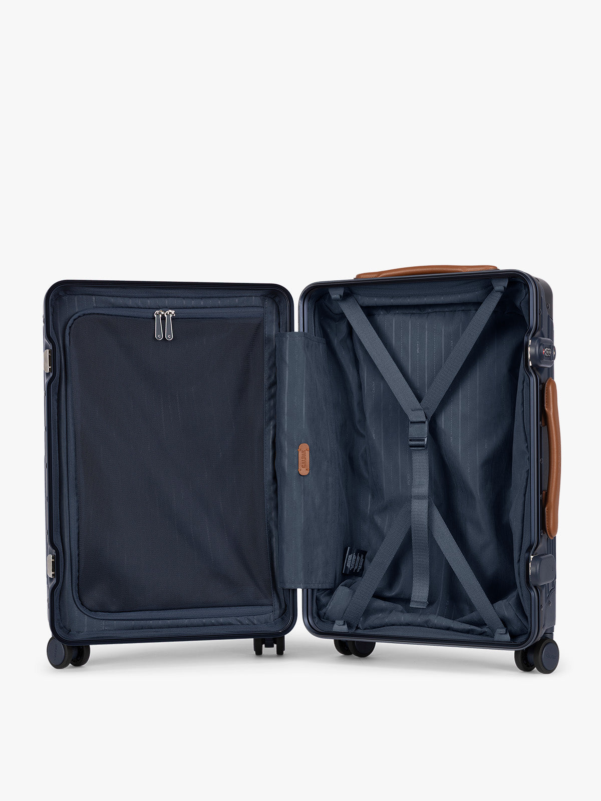 Opened CALPAK Vault Navy blue hard-shell spinner Carry On Luggage with a telescoping handle extended, featuring a brown leatherette side handle and trim, set against a plain light gray background; LVT1020-NAVY