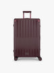 CALPAK Large Vault Luggage in deep red Dark Cherry with hard-shell spinner suitcase with a ribbed vertical design, shown from the front on a light gray background; LVT1028-DARK-CHERRY