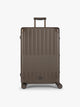 CALPAK Large Vault Luggage in brown Mushroom with hard-shell spinner suitcase with a ribbed vertical design, shown from the front on a light gray background; LVT1028-MUSHROOM