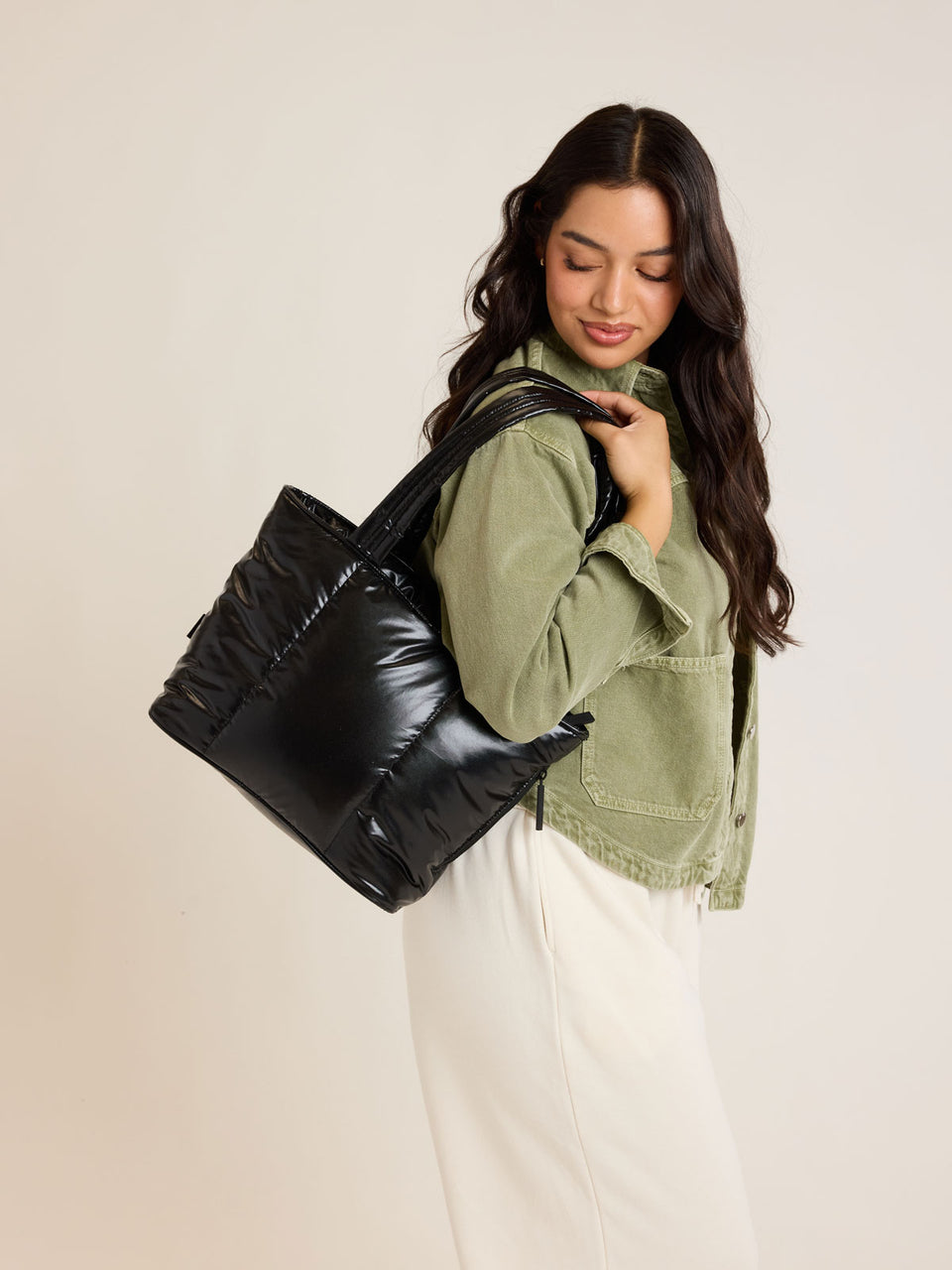 Model wearing CALPAK Luka Mini Tote in shiny Glazed Black on a white background; ALM2401-GLAZED-BLACK
