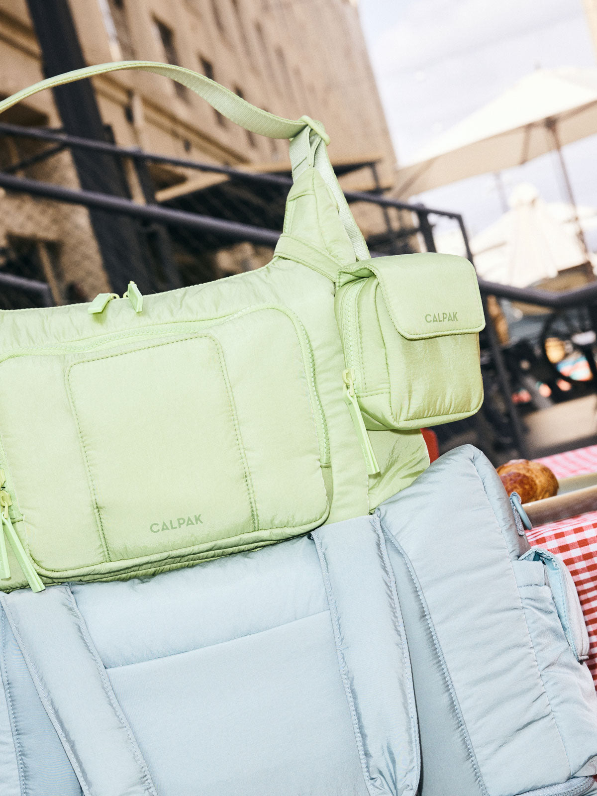 CALPAK Baby Collection Pacifier Pouch in light green Lime clipped onto CALPAK light green Lime Crossbody Diaper Bag; PCB2501-LIME