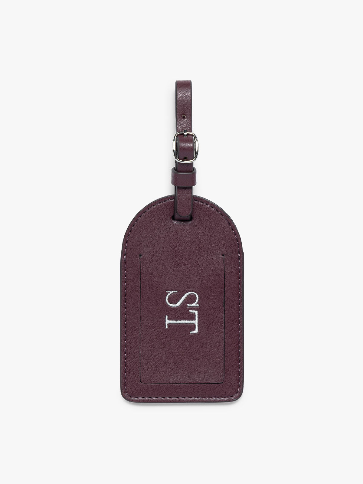 A burgundy CALPAK Luggage Tag with a matching strap with silver metal hardware and a silver monogram "ST" on the front, set against a plain white background; PWTS2601-DARK-CHERRY