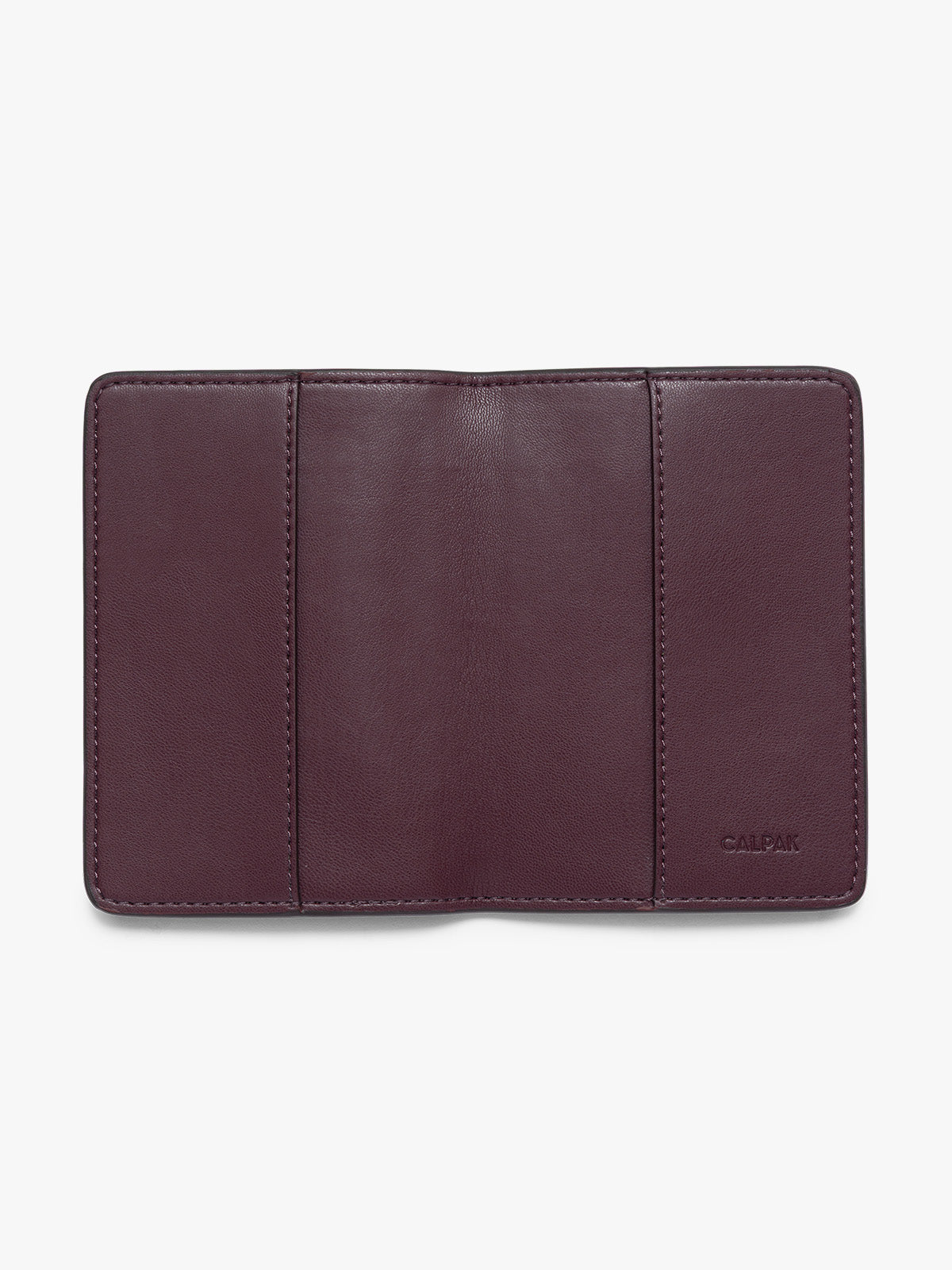 A dark burgundy CALPAK passport HOLDER shown open against a plain white background, featuring the brand name 'CALPAK' debossed on the bottom right; PWTS2601-DARK-CHERRY