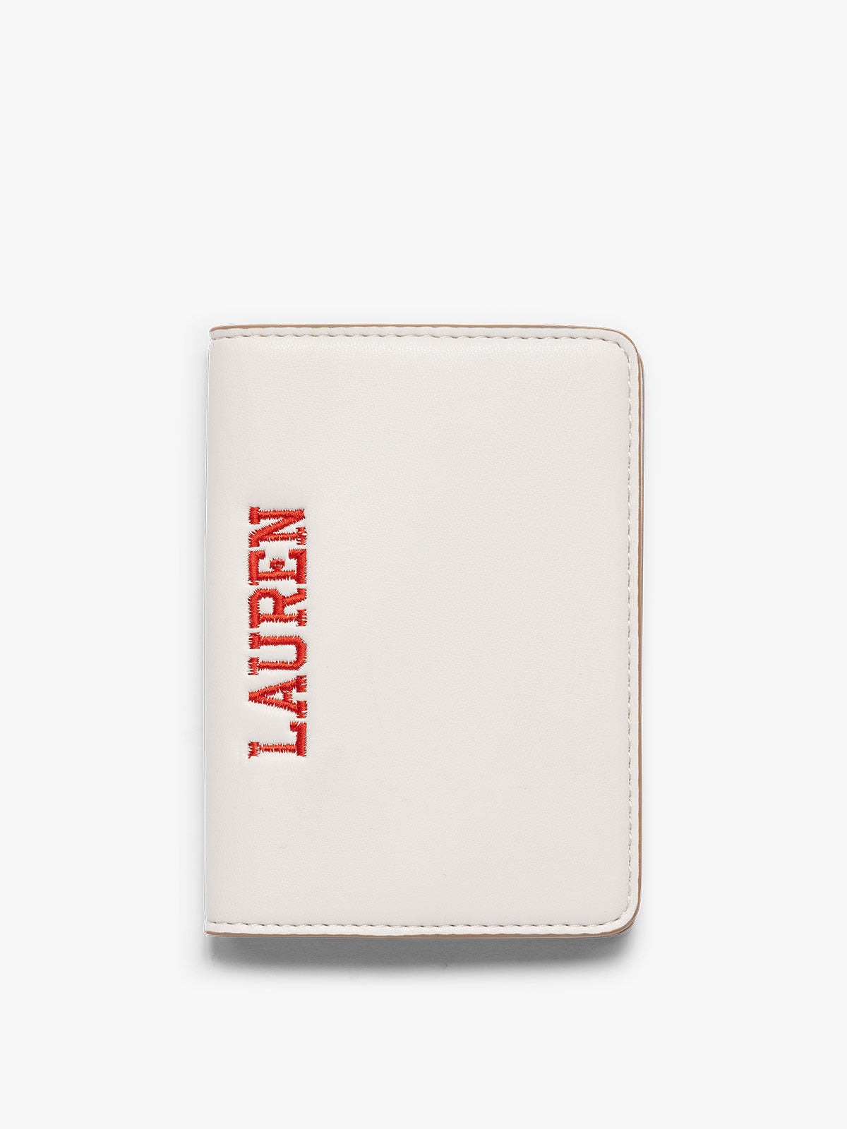 A cream CALPAK Passport Holder with the brand name 'LAUREN' embossed vertically on the front, shown against a plain white background; PWTS2601-VANILLA