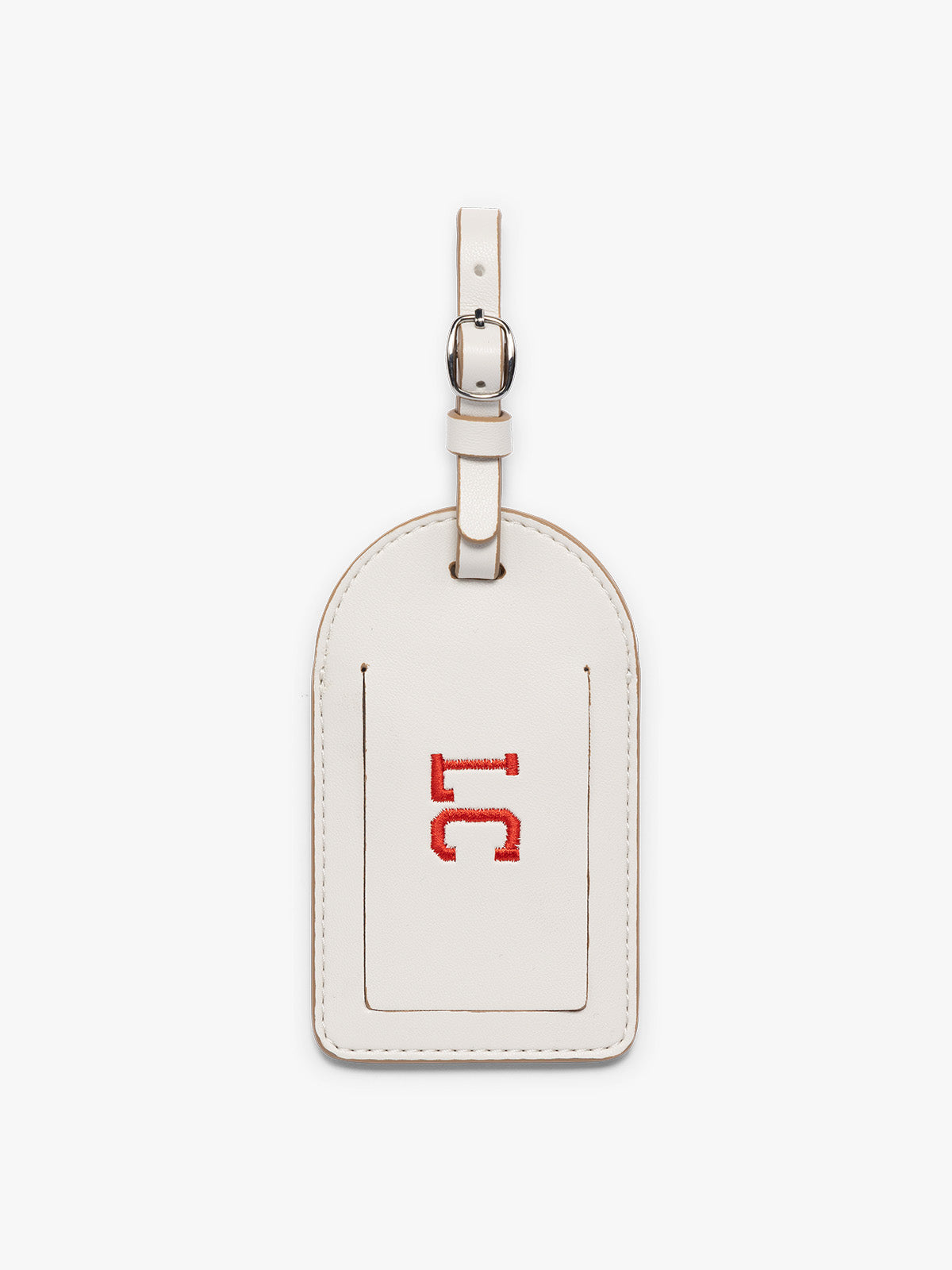 A cream CALPAK Luggage Tag with a matching strap and silver-tone metal buckle, featuring initials "LC" embroidered, shown on a clean white background;  PWTS2601-VANILLA