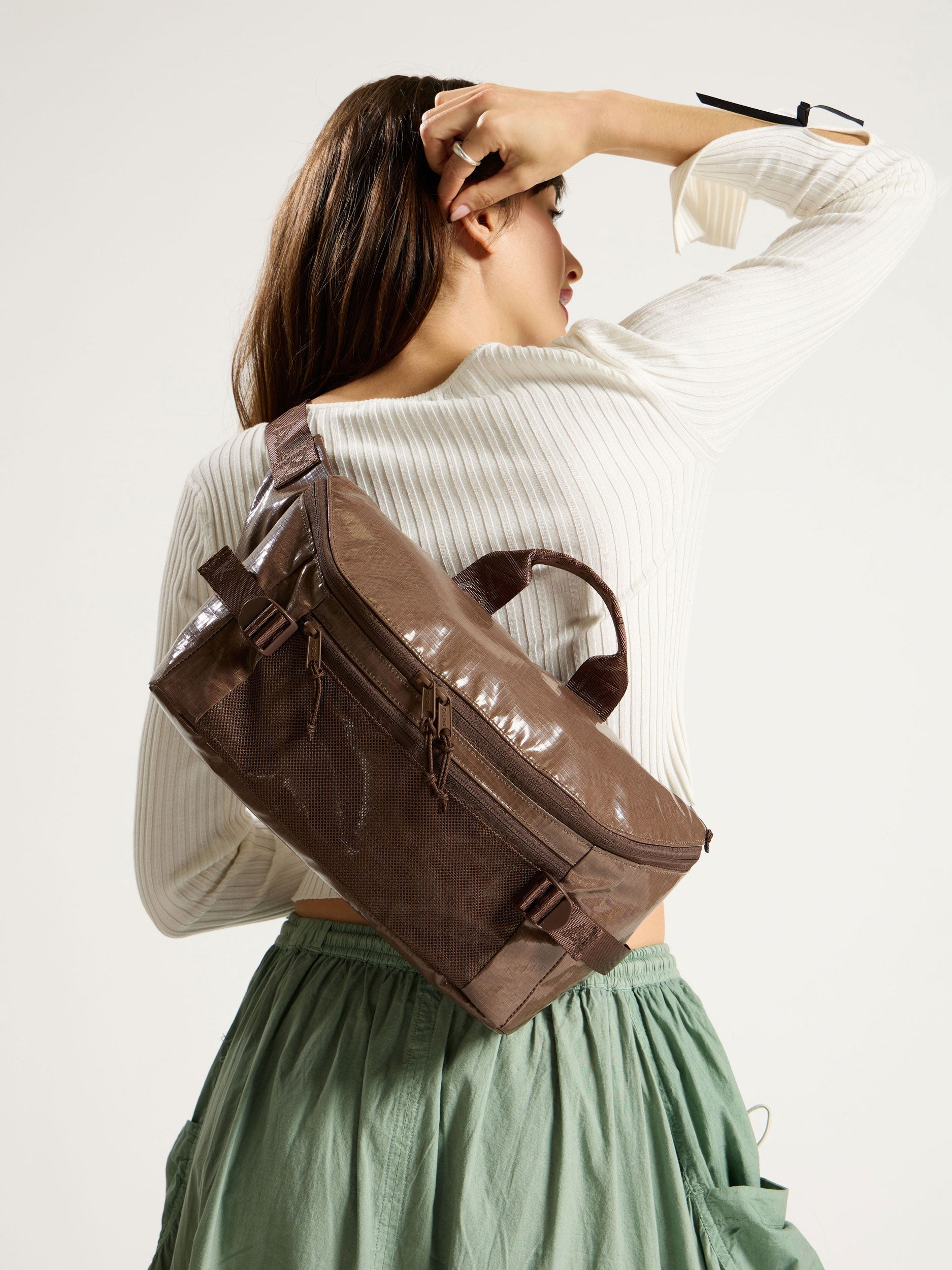 Model wearing CALPAK Terra Sling Bag in chocolate as crossbody bag; CBH2201-CACAO