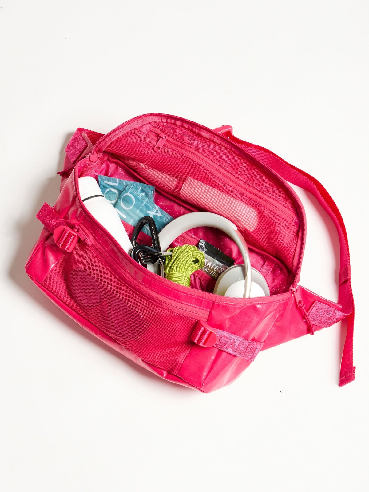 Close of shot of the interior of CALPAK Terra Sling Bag in pink dragonfruit with belongings inside; CBH2201-DRAGONFRUIT