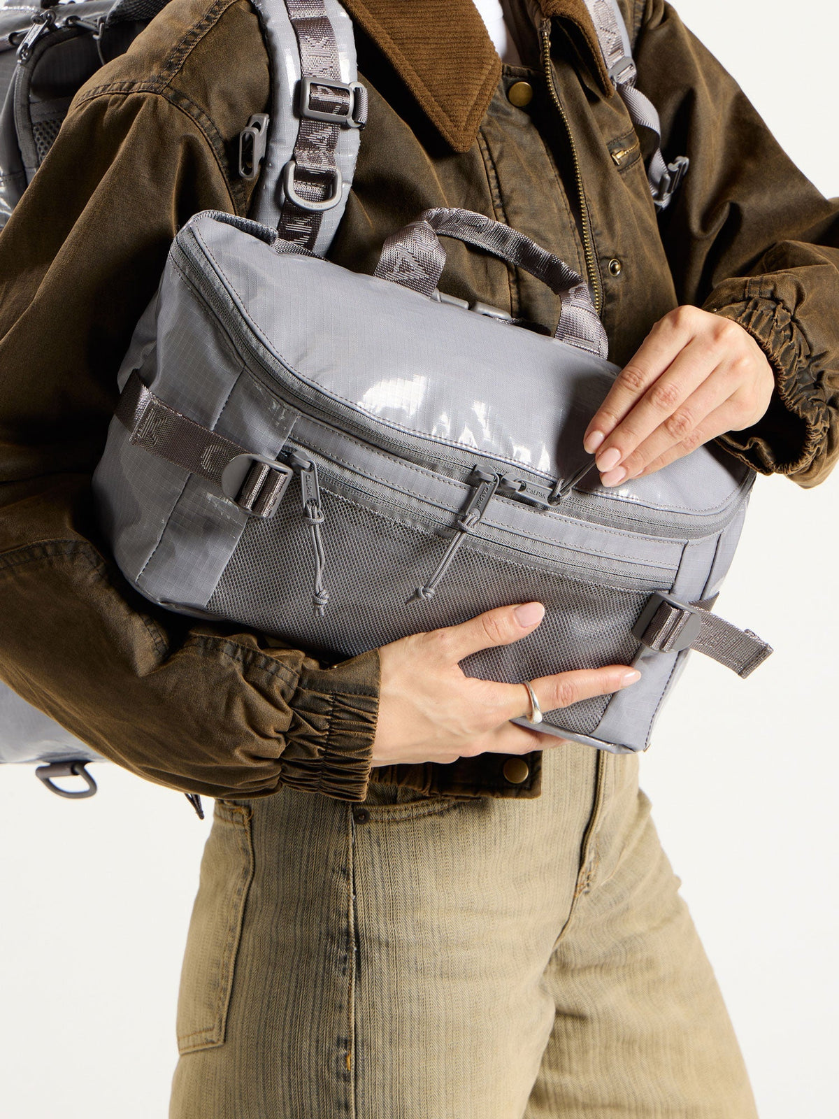 Model showing main zippered compartment of CALAPK Terra Sling Bag in gray; CBH2201-STORM