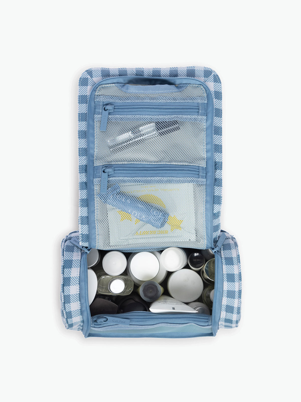 Toiletries in the CALPAK Luka Hanging Toiletry Bag in white and blue gingham print in French Blue Gingham; TLH2301-FRENCH-BLUE-GINGHAM