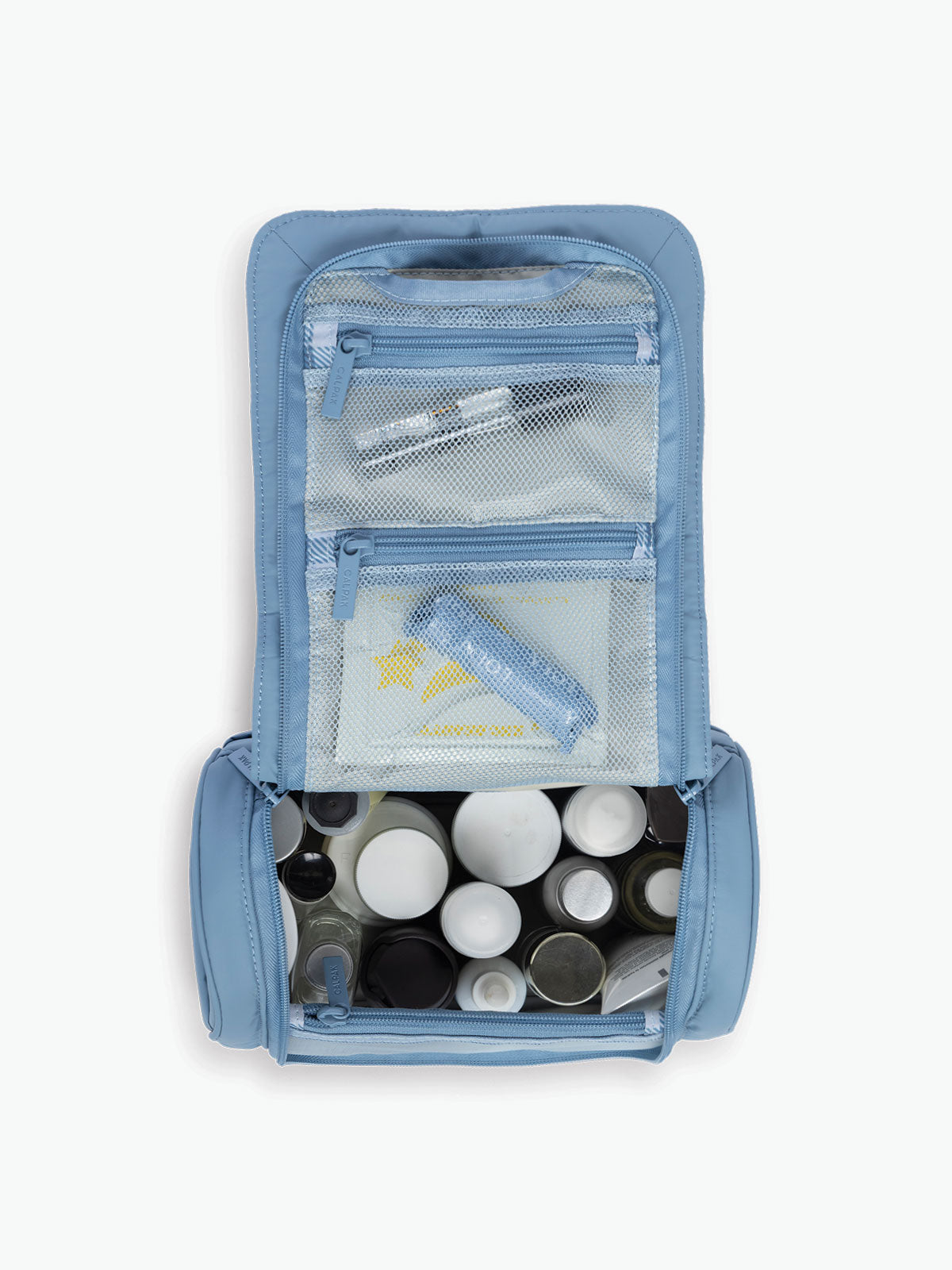 Opened with toiletries of the CALPAK Luka Hanging Toiletry Bag in light blue French Blue; TLH2301-FRENCH-BLUE