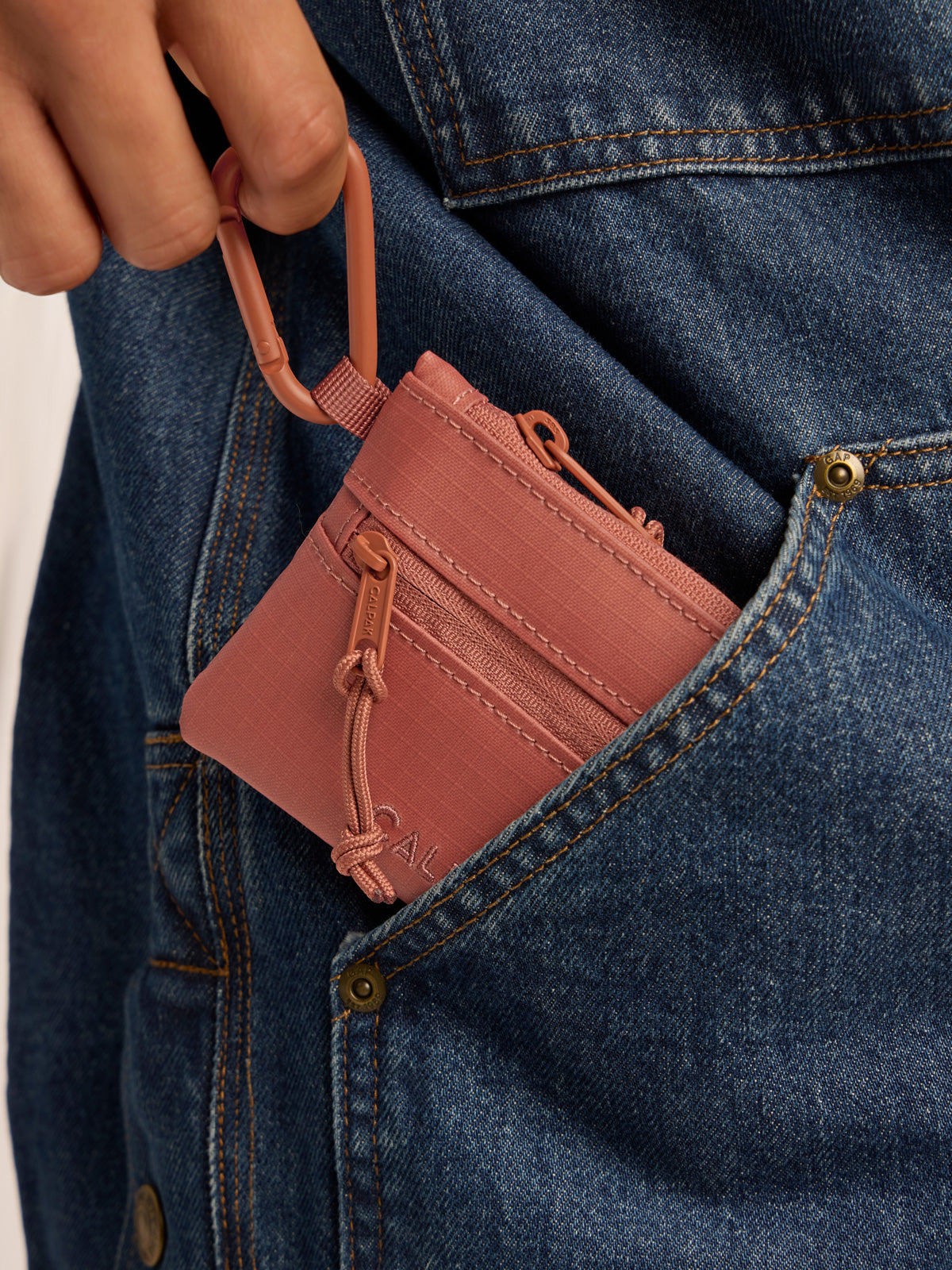 Model clipping in the CALPAK Terra Clippable Card Pouch in red and orange Matte Clay; TPC2401-CLAY