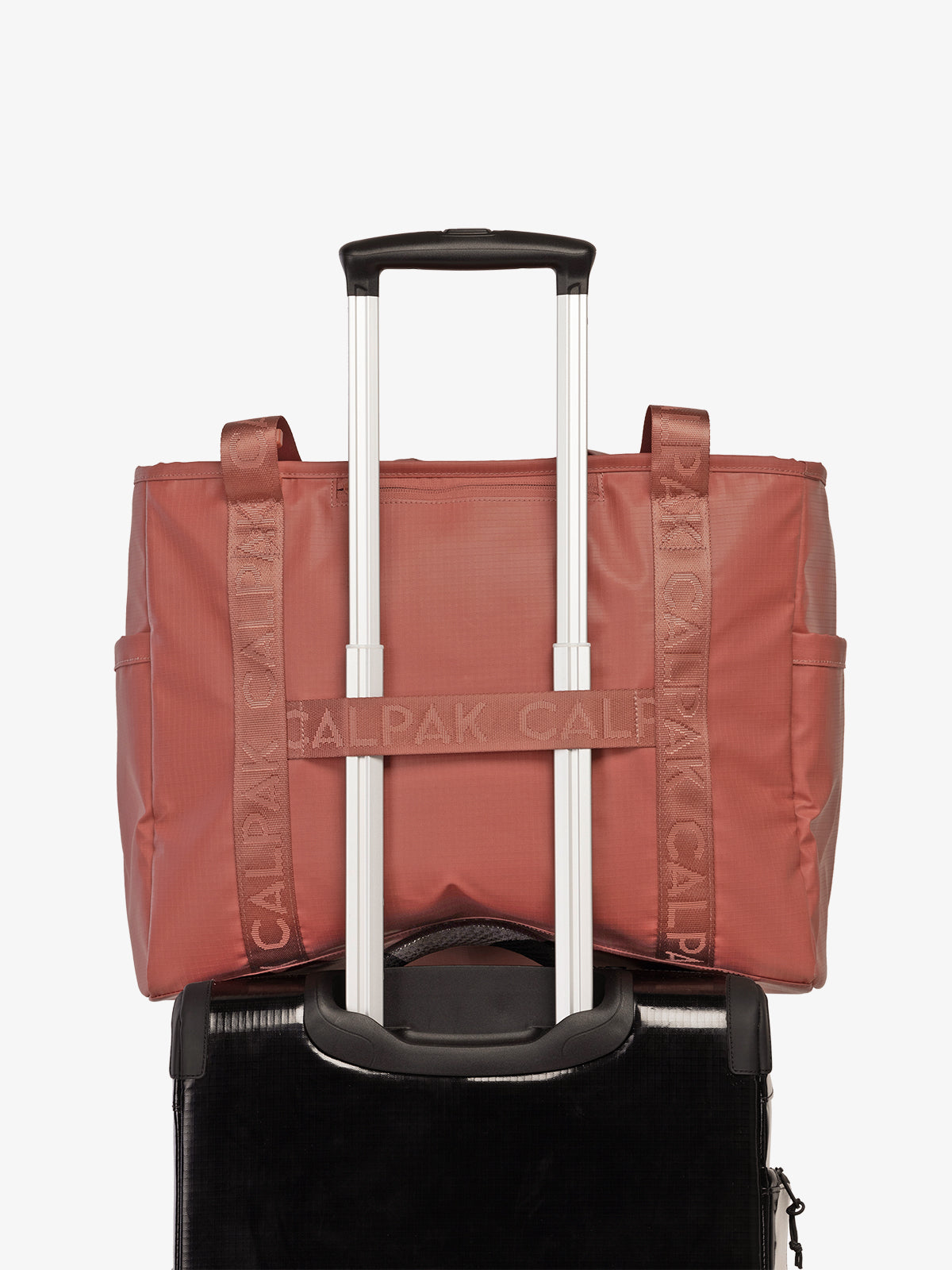 CALPAK Terra 35L Water Resistant Zippered Tote Bag in red and orange Matte Clay on suitcase with trolley sleeve; TTO2401-CLAY