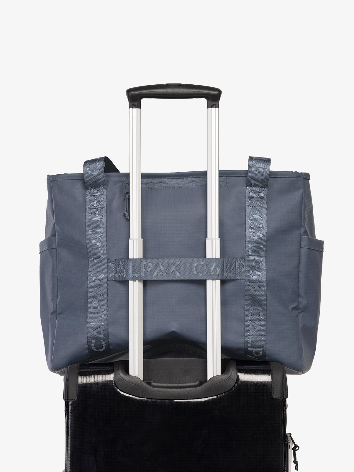 CALPAK Terra 35L Water Resistant Zippered Tote Bag in blue Matte Indigo on suitcase with trolley sleeve; TTO2401-INDIGO