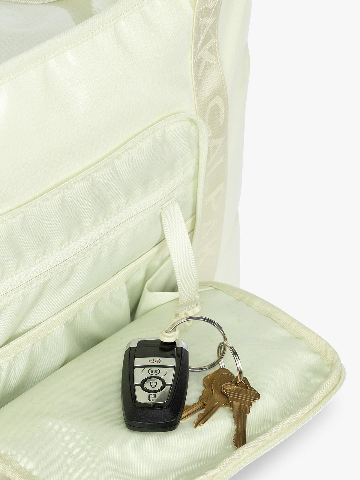 Front pocket key leash of the CALPAK Terra 35L Tote Bag with multiple pockets and shoulder straps in shiny light green Celadon on a white background; TTO2401-CELADON