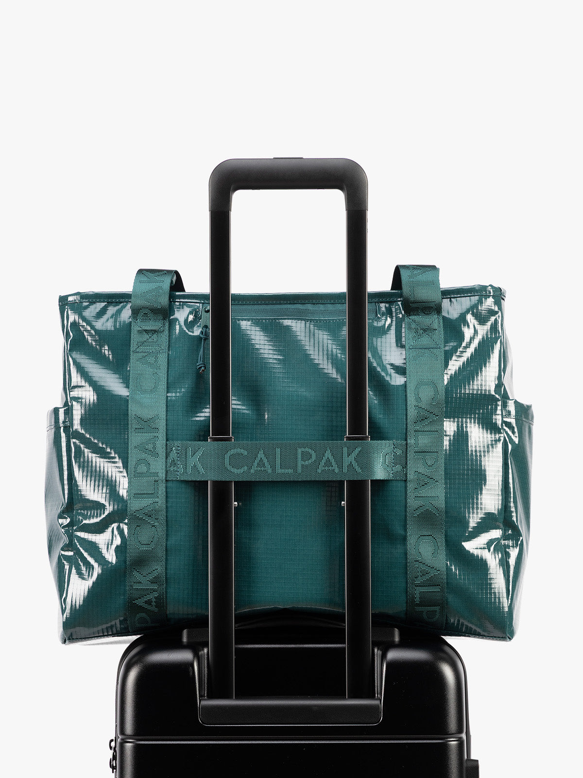 Back trolley sleeve of CALPAK Terra 35L Tote Bag with zippers in blue green Kale on a white background; TTO2401-KALE