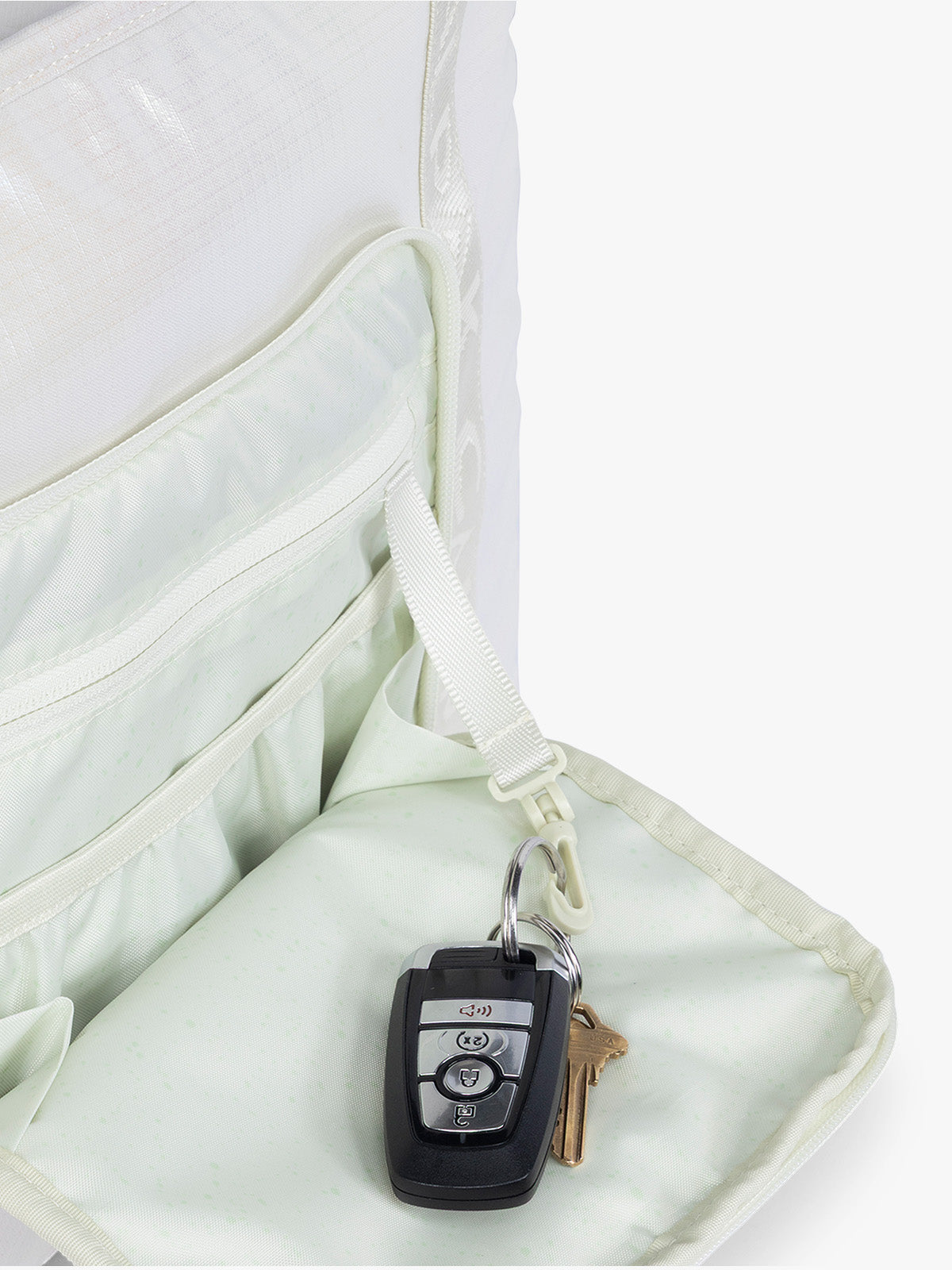 Key leash in the front pocket of the CALPAK Terra 35L Tote Bag with multiple pockets and shoulder straps in shiny white Moonbeam on a white background; TTO2401-MOONBEAM