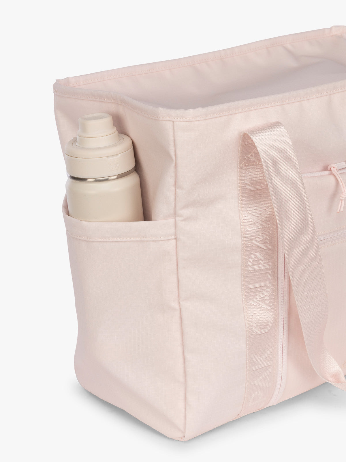 Side water bottle compartment pocket of the CALPAK Terra 35L Tote Bag with multiple pockets and shoulder straps in shiny light pink Shell Pink on a white background; TTO2401-SHELL-PINK