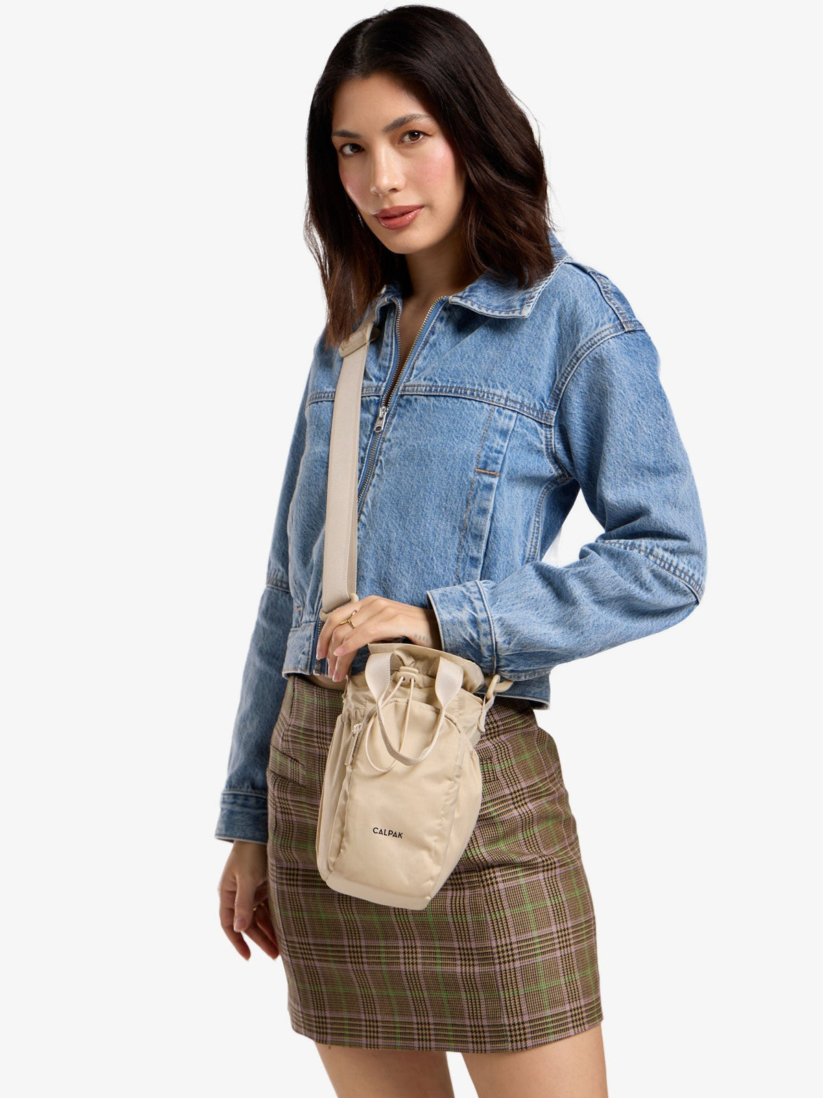 Model wearing beige CALPAK water bottle bag as crossbody bag; AWH2101-OATMEAL