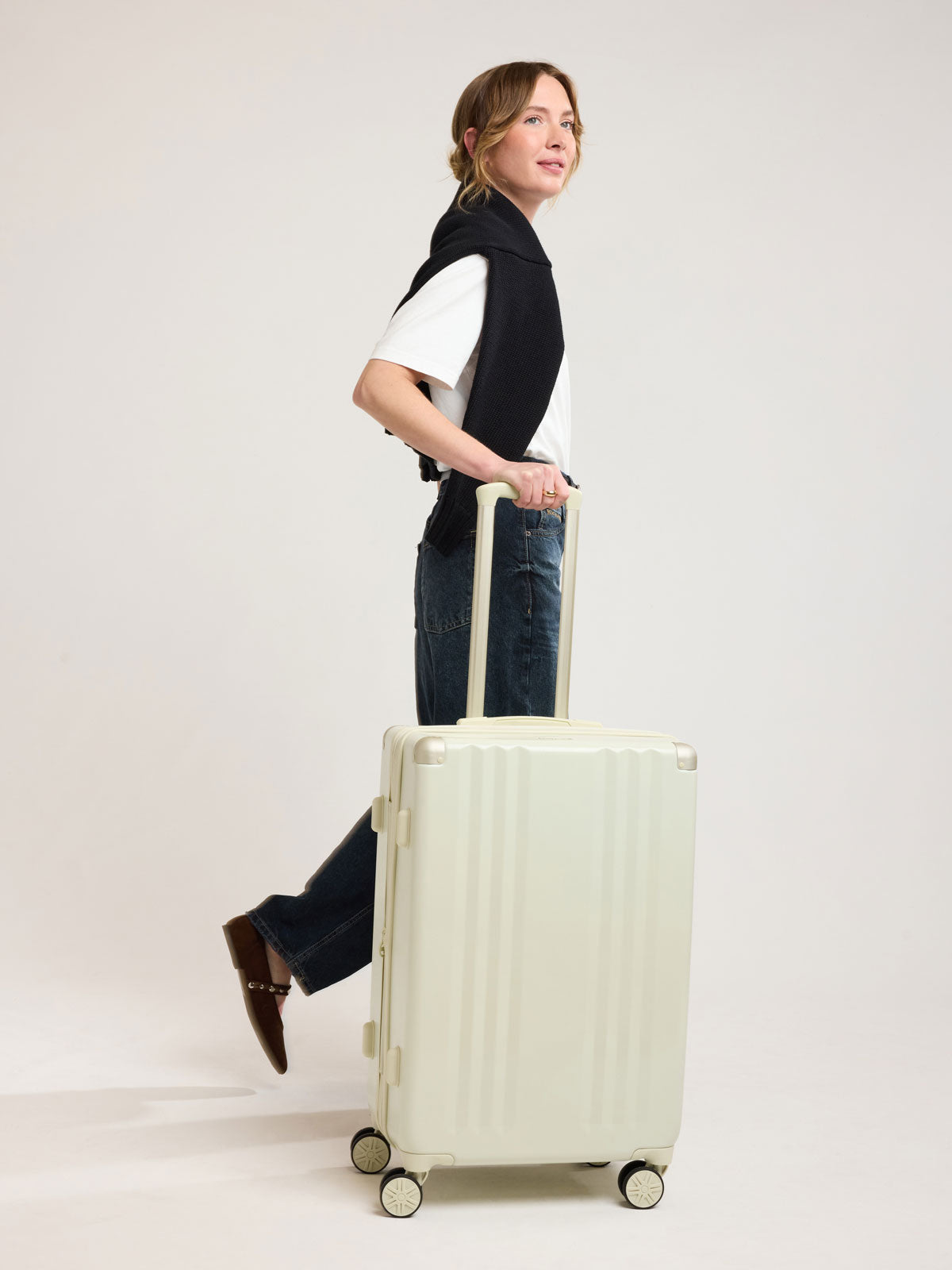Woman with CALPAK Ambeur Medium Luggage in light green Celadon; LAM1024-CELADON