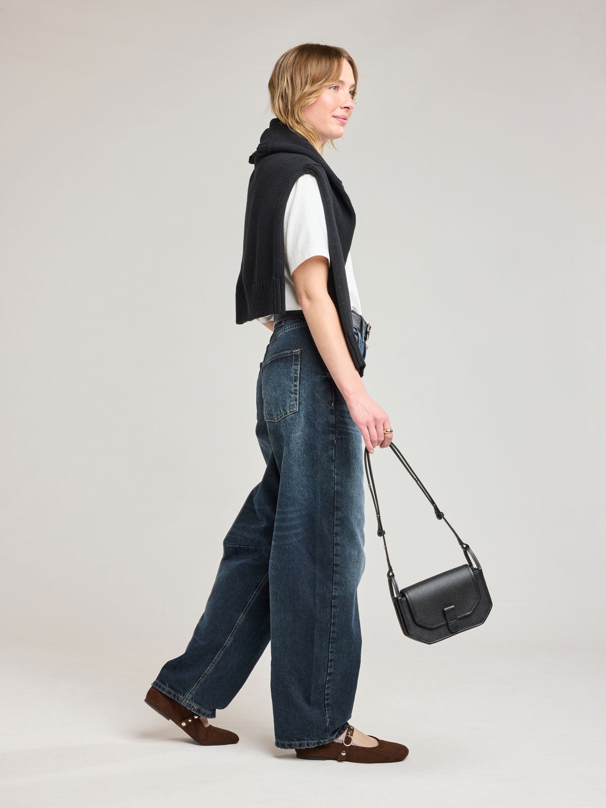 Woman holding CALPAK Colette Canvas Crossbody Wallet Bag in black canvas material ; CLWC2601-BLACK