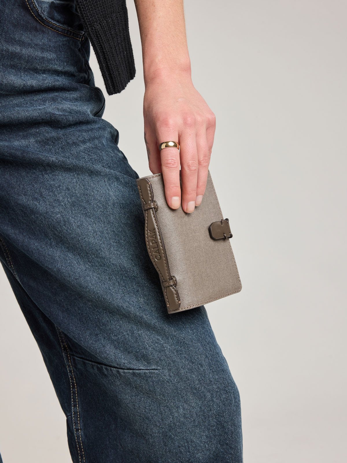 Person holding CALPAK Colette Multi Passport Wallet in brown Mushroom canvas material; CLPW2601-MUSHROOM