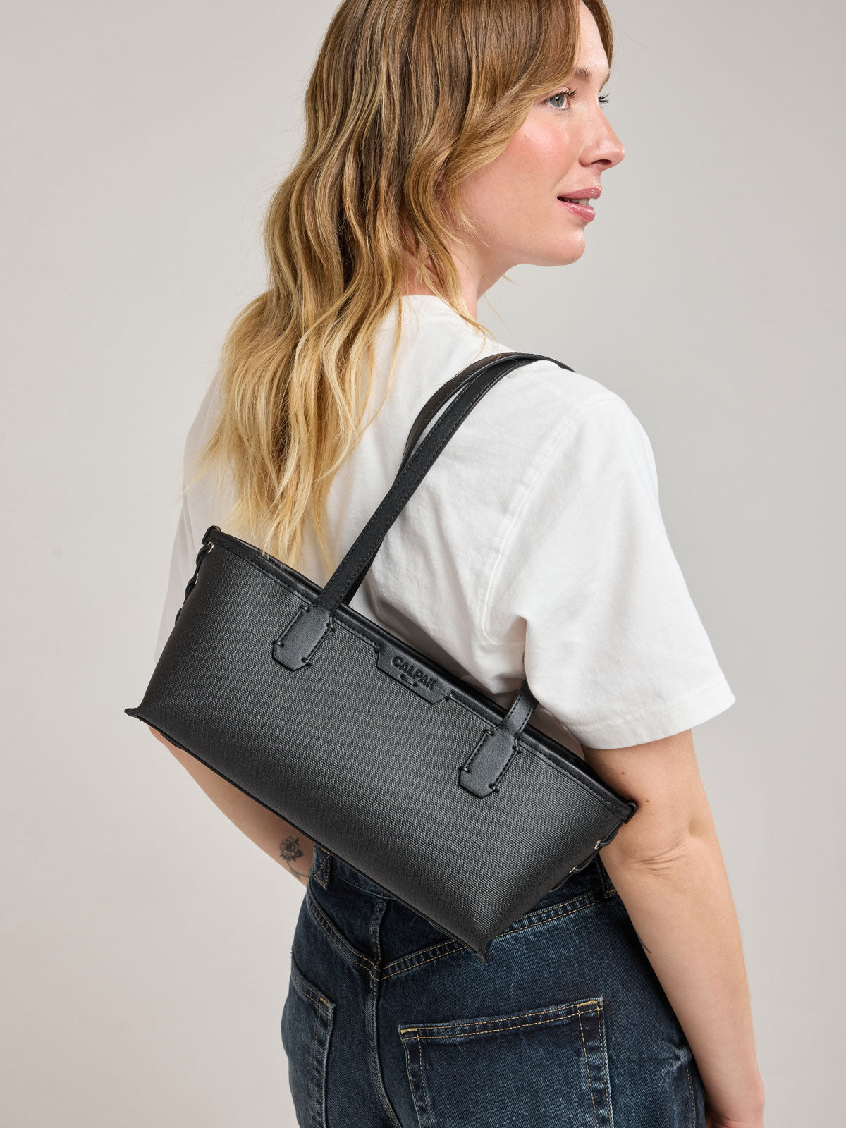 Woman wearing CALPAK Colette Canvas Shoulder Tote in Black canvas material ; CLST2601-BLACK