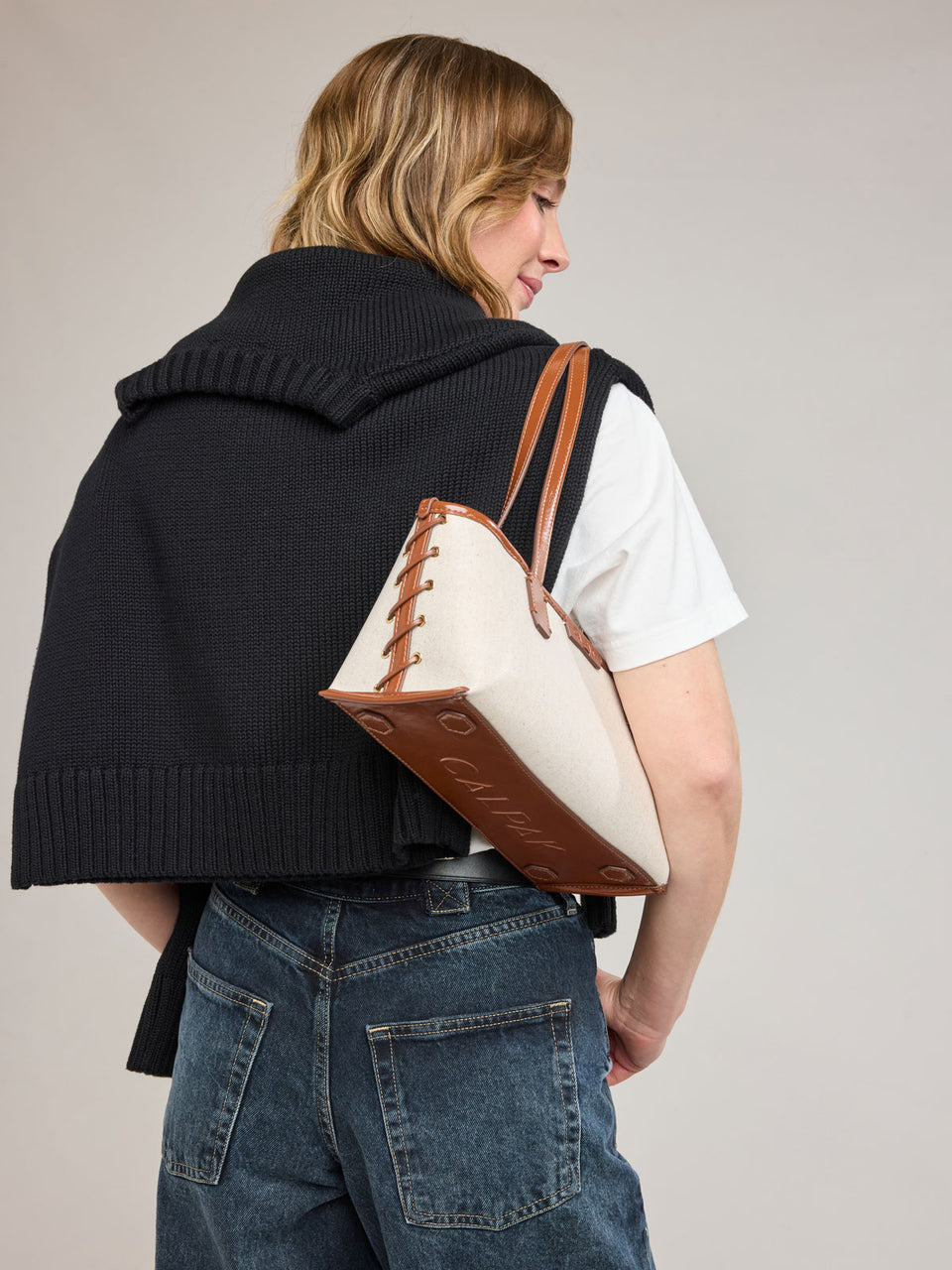 Woman wearing CALPAK Colette Canvas Shoulder Tote in beige canvas material and brown finishing; CLST2601-NATURAL-BROWN