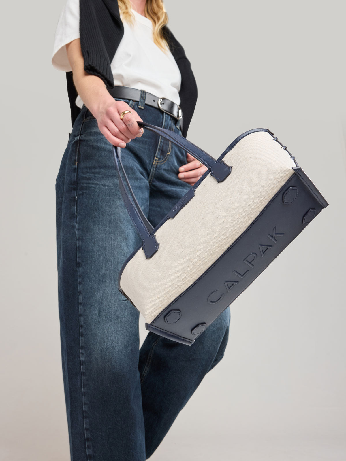 Woman holding CALPAK Colette Canvas Shoulder Tote in beige canvas material  and blue finishing; CLST2601-NATURAL-NAVY