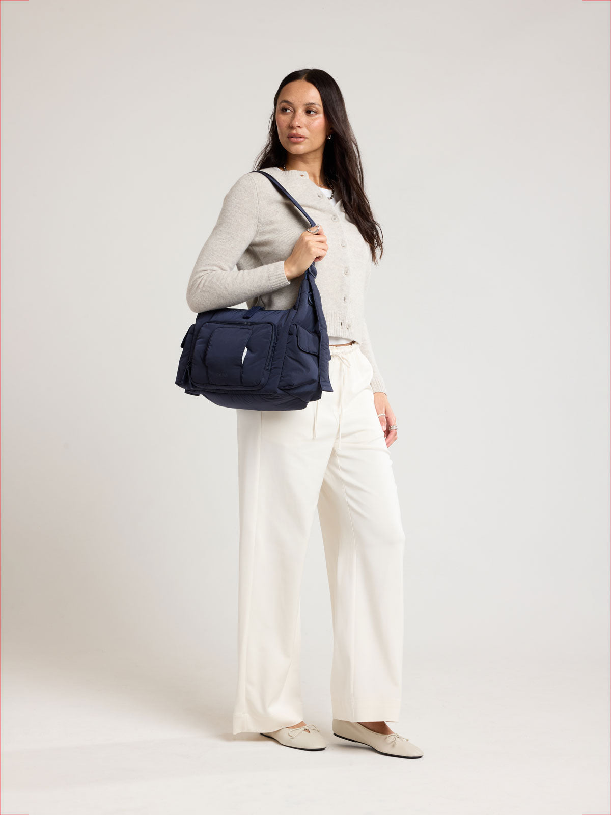 Woman wearing CALPAK Crossbody Diaper Bag in blue Navy; CDB2501-NAVY