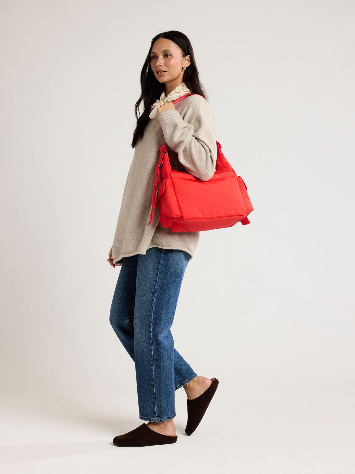 Woman wearing CALPAK Crossbody Diaper Bag in red Tomato; CDB2501-TOMATO