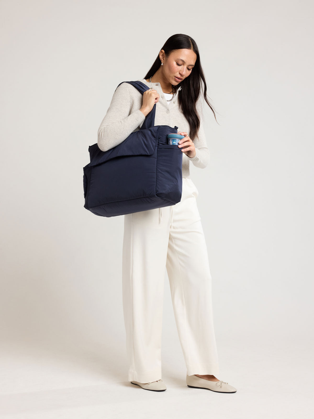 Woman wearing CALPAK Diaper Tote bag in blue Navy; TBB2401-NAVY