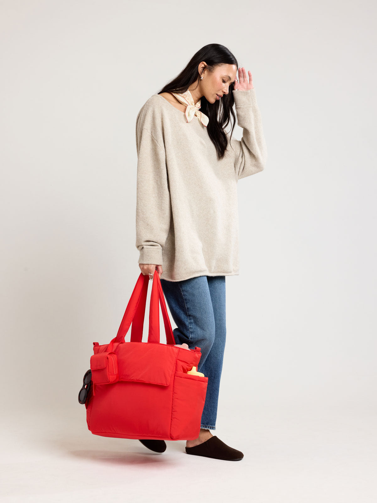 Woman holding CALPAK Diaper Tote bag in red Tomato; TBB2401-TOMATO