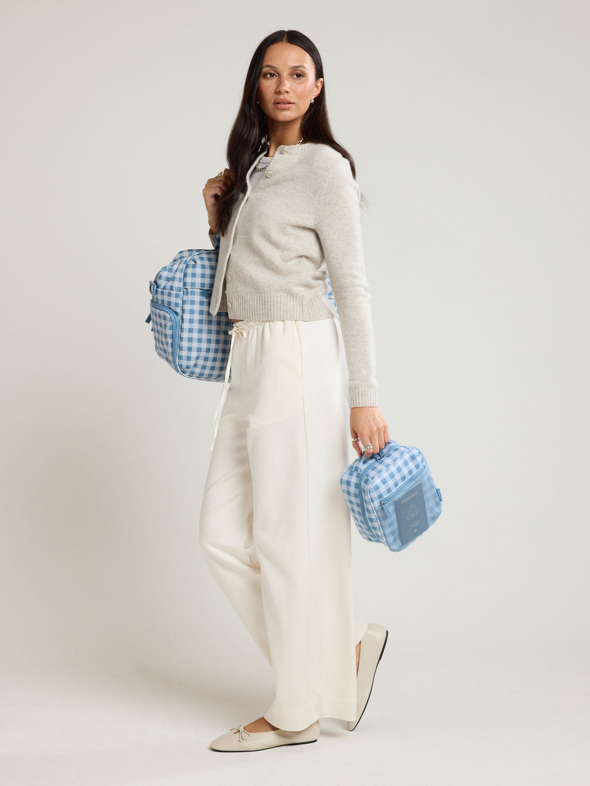 Woman holding the CALPAK Everything Cube in light blue and white gingham print ; ACE2401-FRENCH-BLUE-GINGHAM