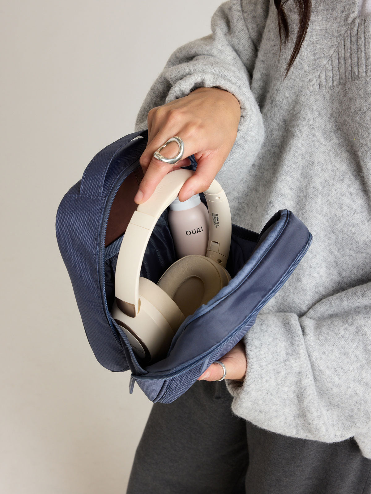 Person adding headphones into the CALPAK Everything Cube in dark blue Indigo ; ACE2401-INDIGO