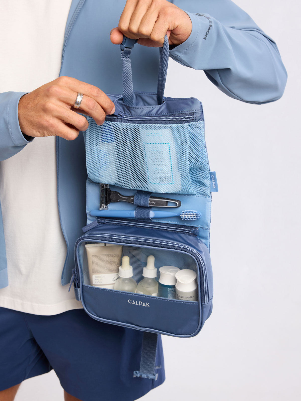 Model holding open the CALPAK Fit Hanging Dopp Kit in blue Indigo ; TFH2401-INDIGO