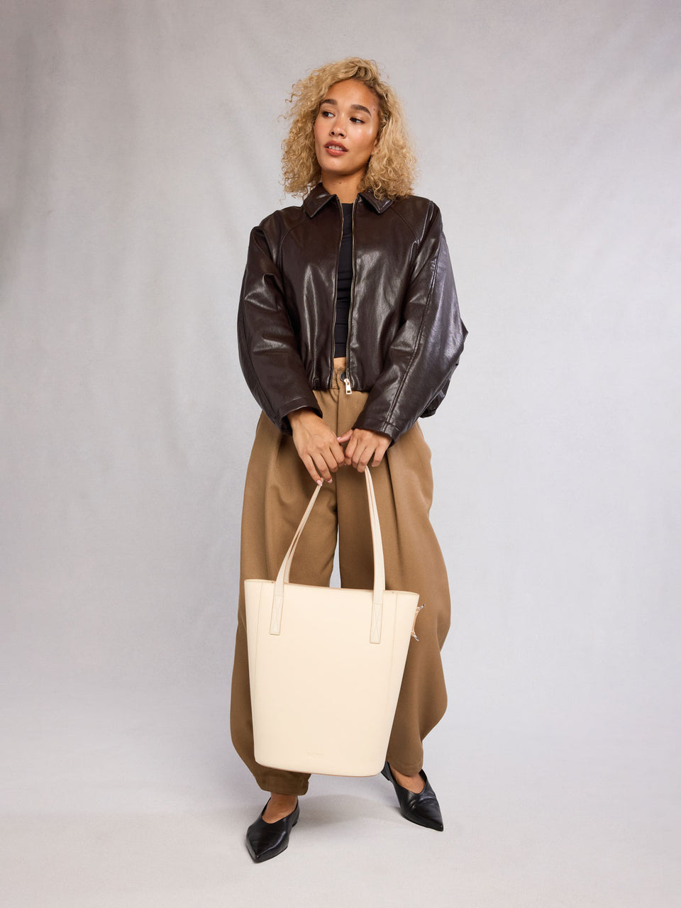 Woman holding the CALPAK Haven 14" Haven Laptop Tote in white beige Buttercream; ABU2501-BUTTERCREAM