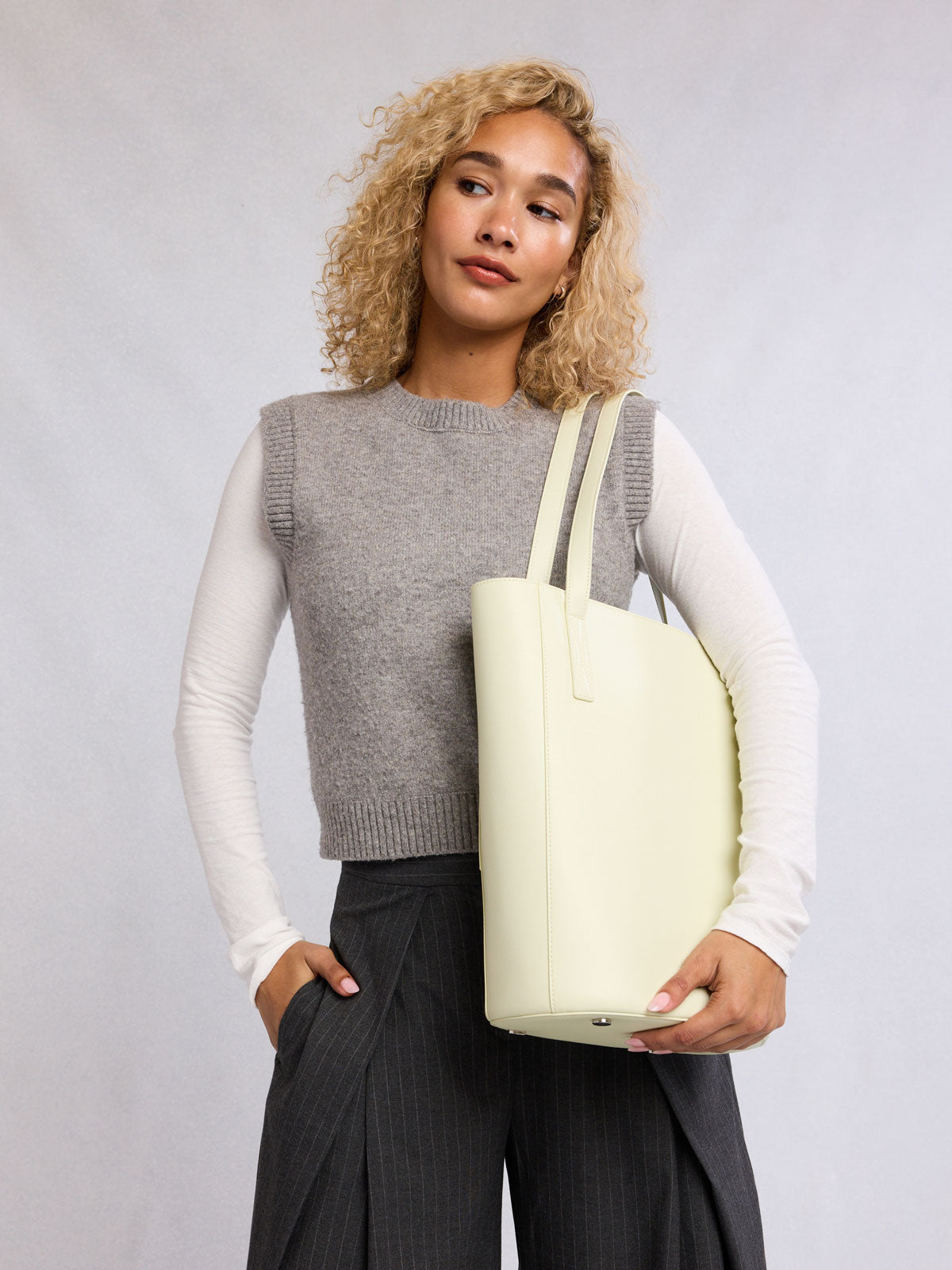 Woman wearing the CALPAK Haven 14" Haven Laptop Tote in light green Celadon; ABU2501-CELADON