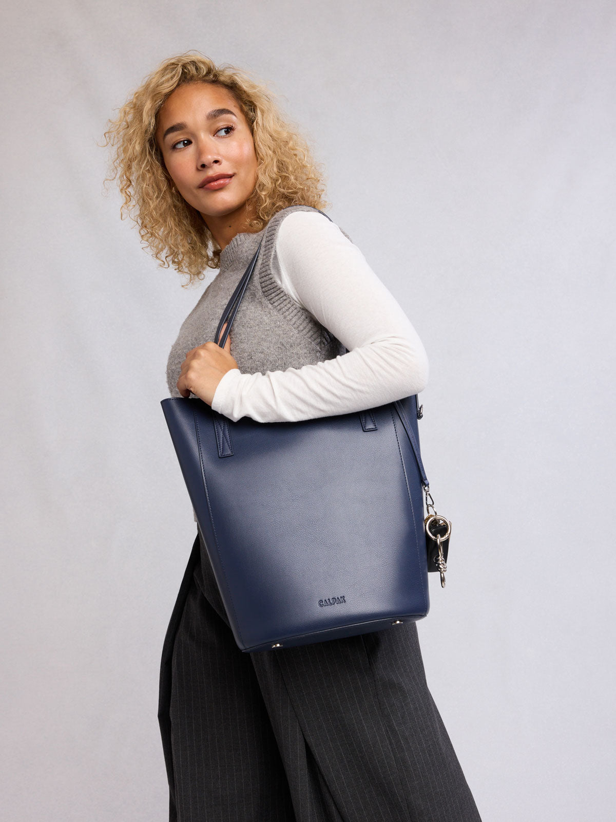 Woman holding the CALPAK Haven 14" Haven Laptop Tote in dark blue Navy; ABU2501-NAVY