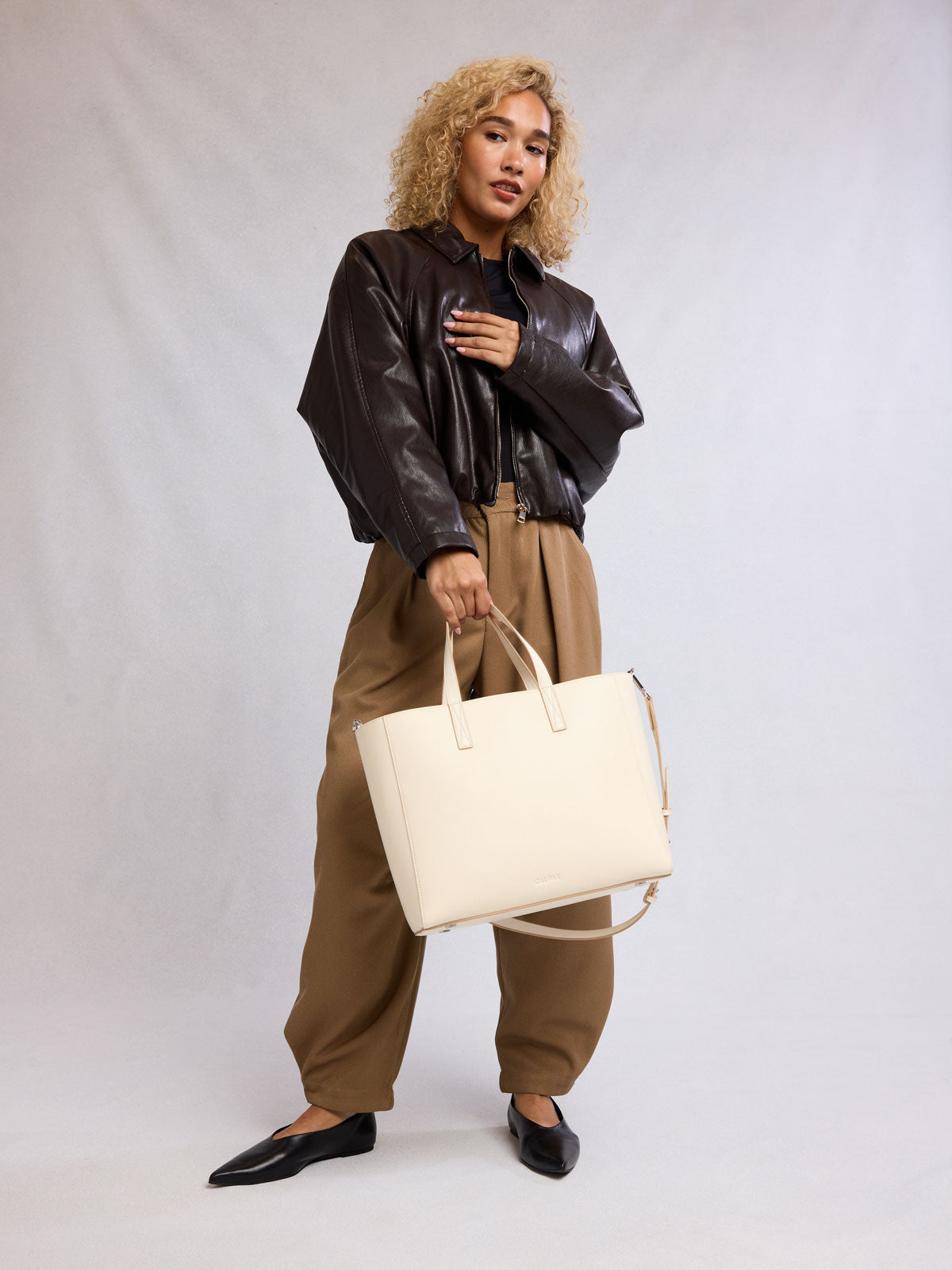 Person holding a CALPAK Haven 15" Laptop Tote in beige Buttercream; ATS2501-BUTTERCREAM