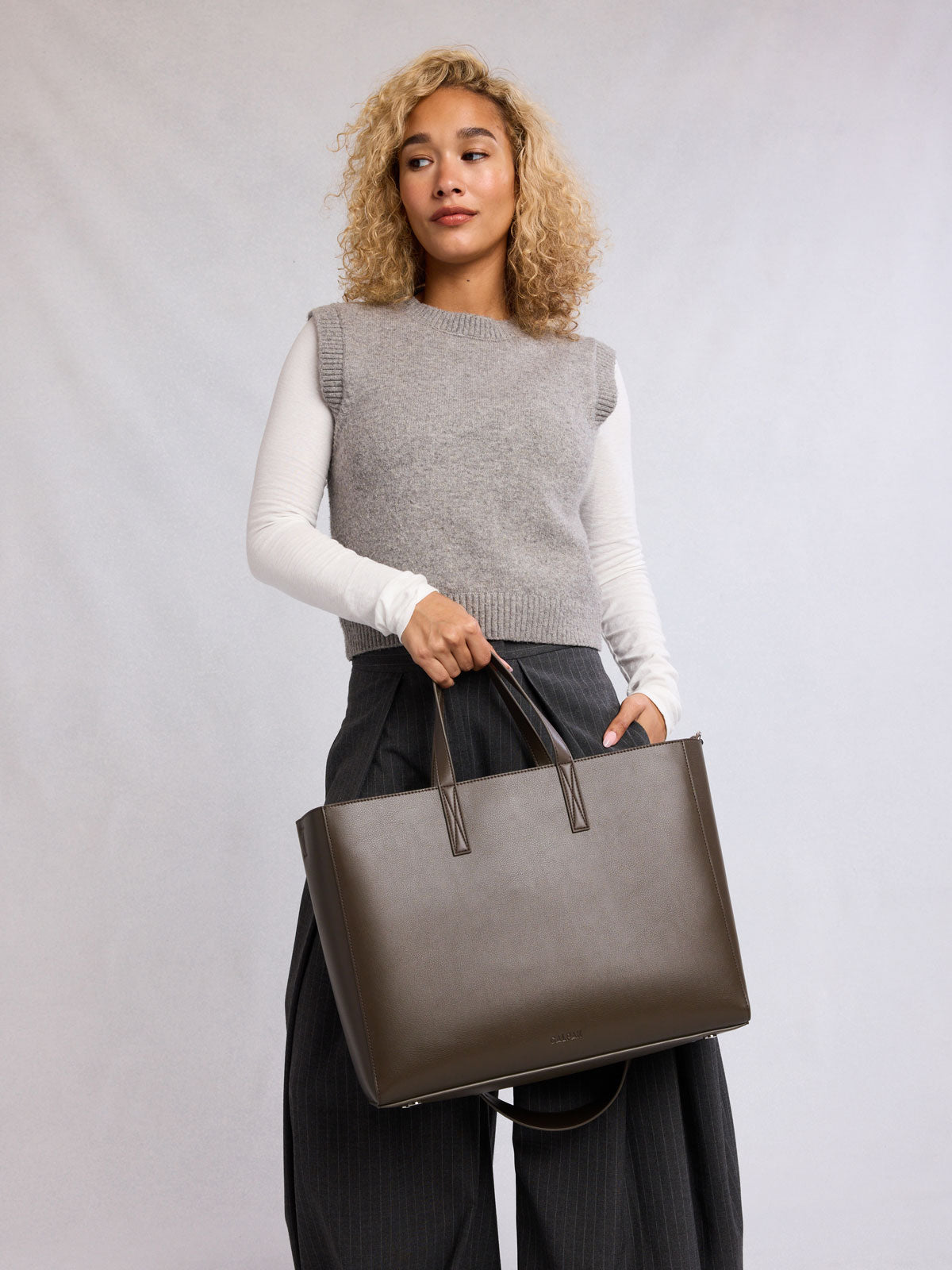 Model wearing CALPAK Haven 16" Laptop Tote in dark brown Mushroom; ATO2102-MUSHROOM