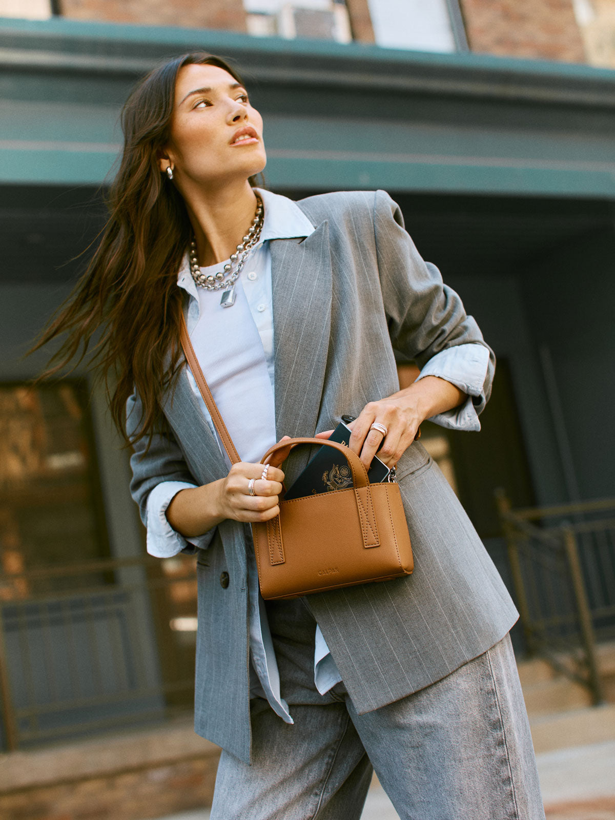 CALPAK Haven Mini Crossbody Bag in brown Toffee being worn by model; AMC2501-TOFFEE
