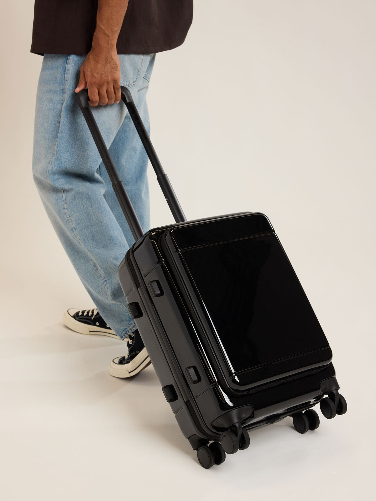 Model with CALPAK Hue Front Pocket Carry On Luggage in Glazed Black; LHU1020-GLAZED-BLACK
